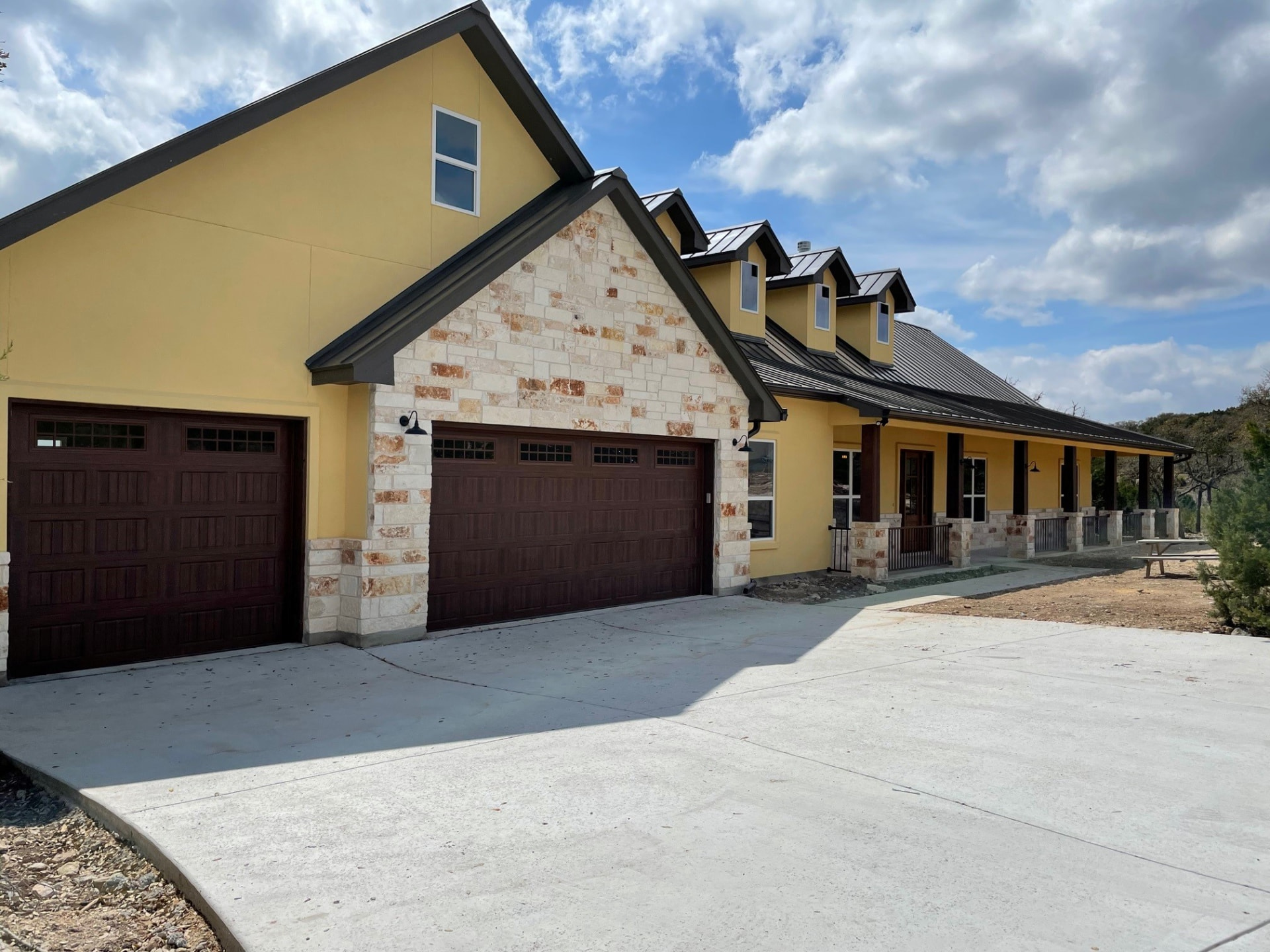 The Pipe Creek home in stucco and native stone with a metal roof and attached garage