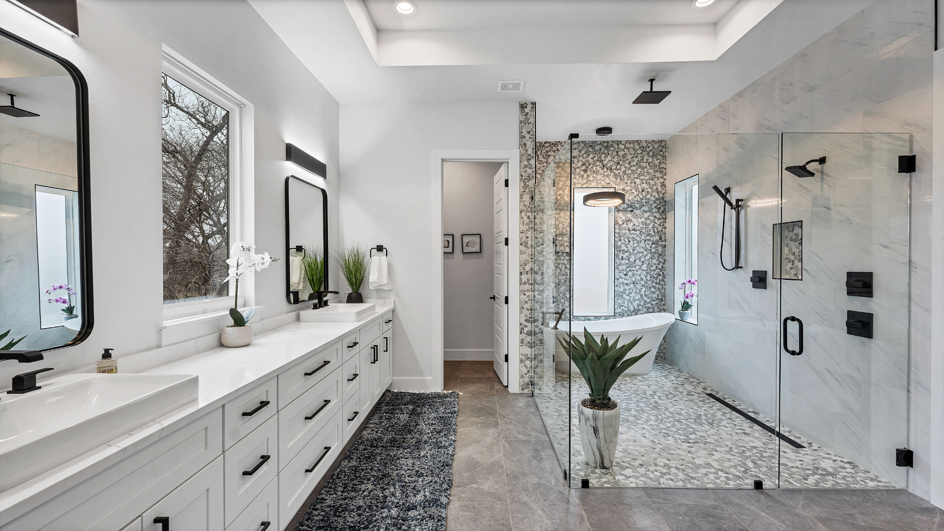 Finished primary bathroom with double vanity, freestanding tub, and glass shower