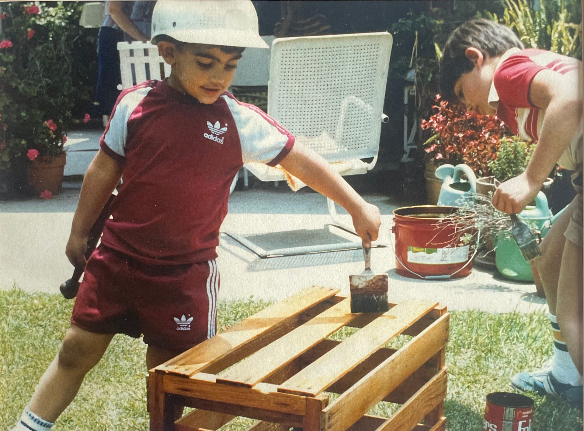 Two young brothers staining a wooden bench in a backyard in the 1980s