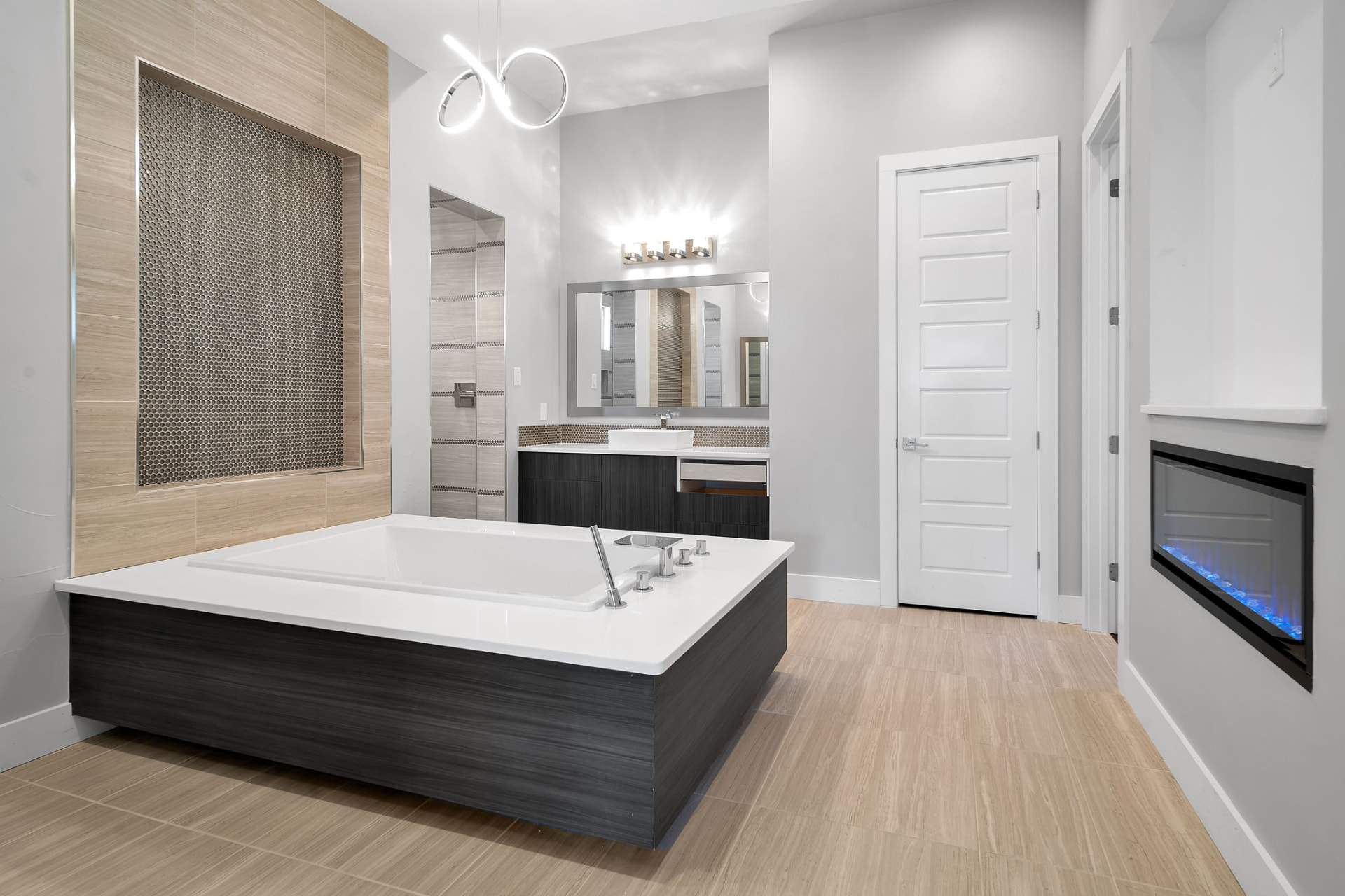 Primary bathroom with a deck mounted soaking tub, linear fireplace, and vanity