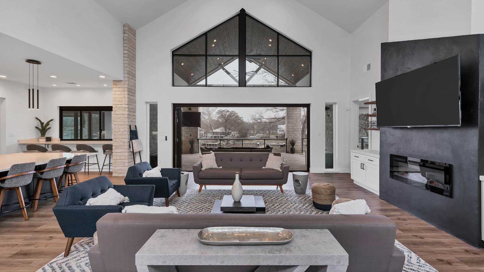 Living room with a gable window wall and the accordion door open to the porch