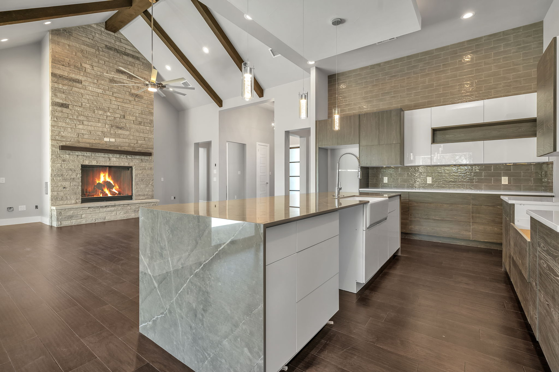Open-plan kitchen and living room of a finished custom home with vaulted ceilings and a stone fireplace