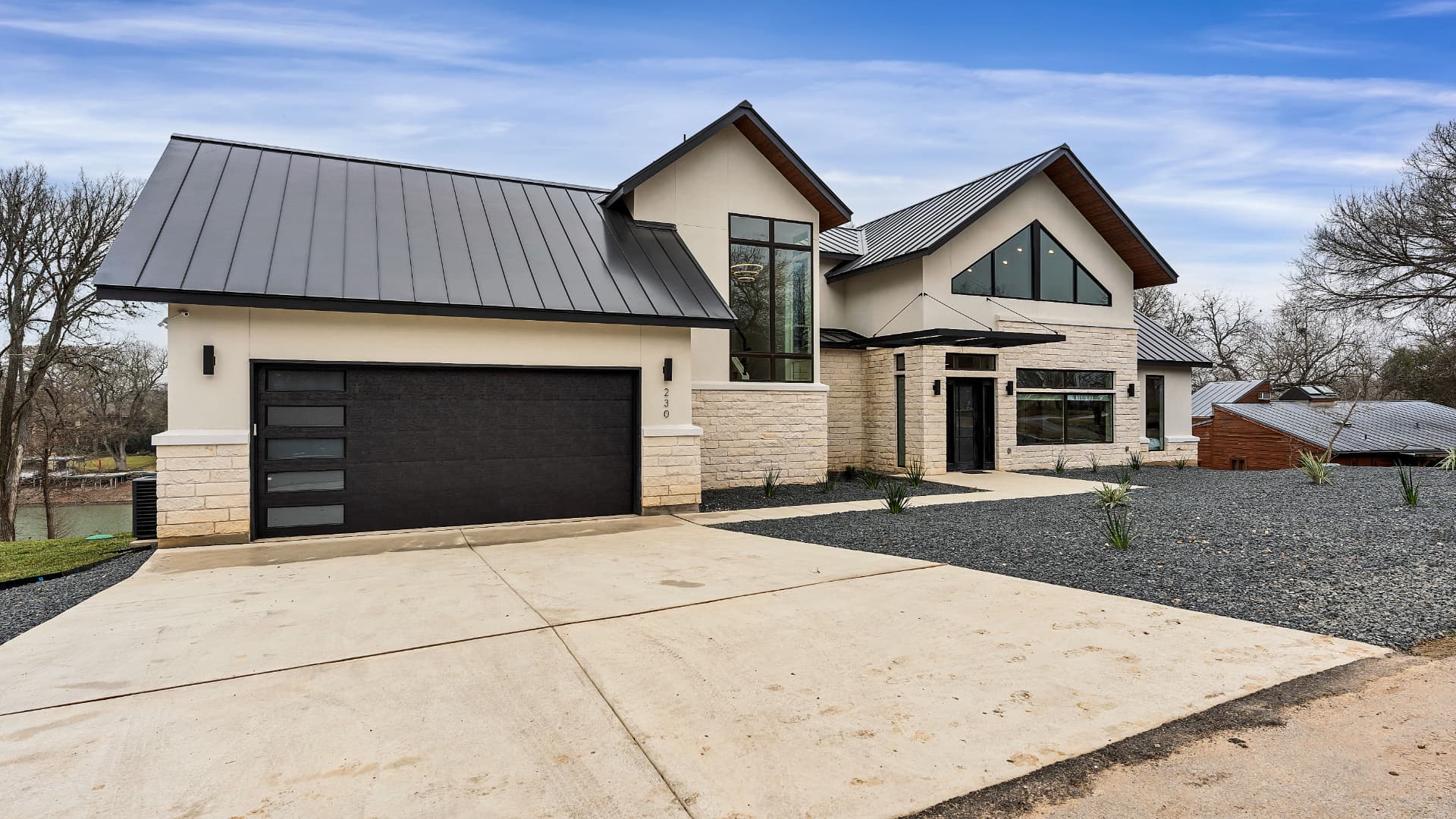 Stone and stucco custom home near Lake Placid with steep metal gables and black-framed windows